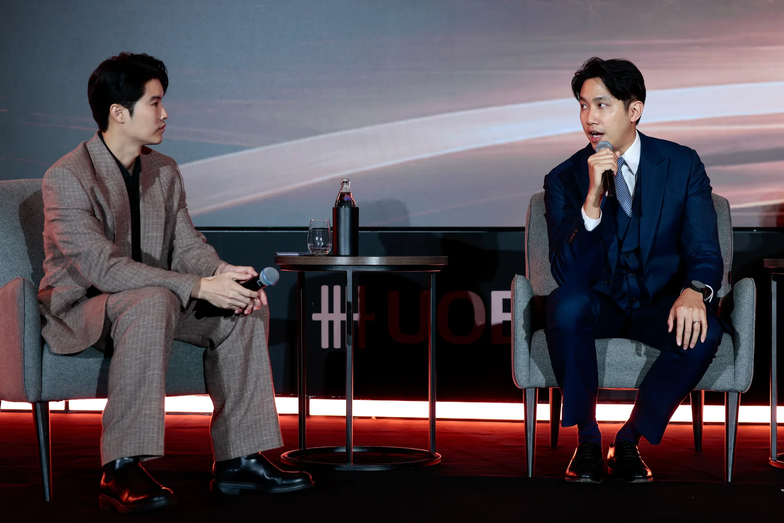 Two speakers exchanging ideas in a seated discussion.