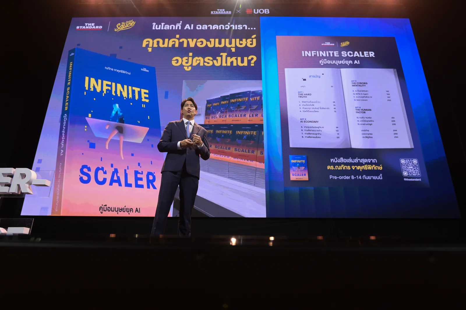 A speaker presenting beside the Infinite Scaler book.