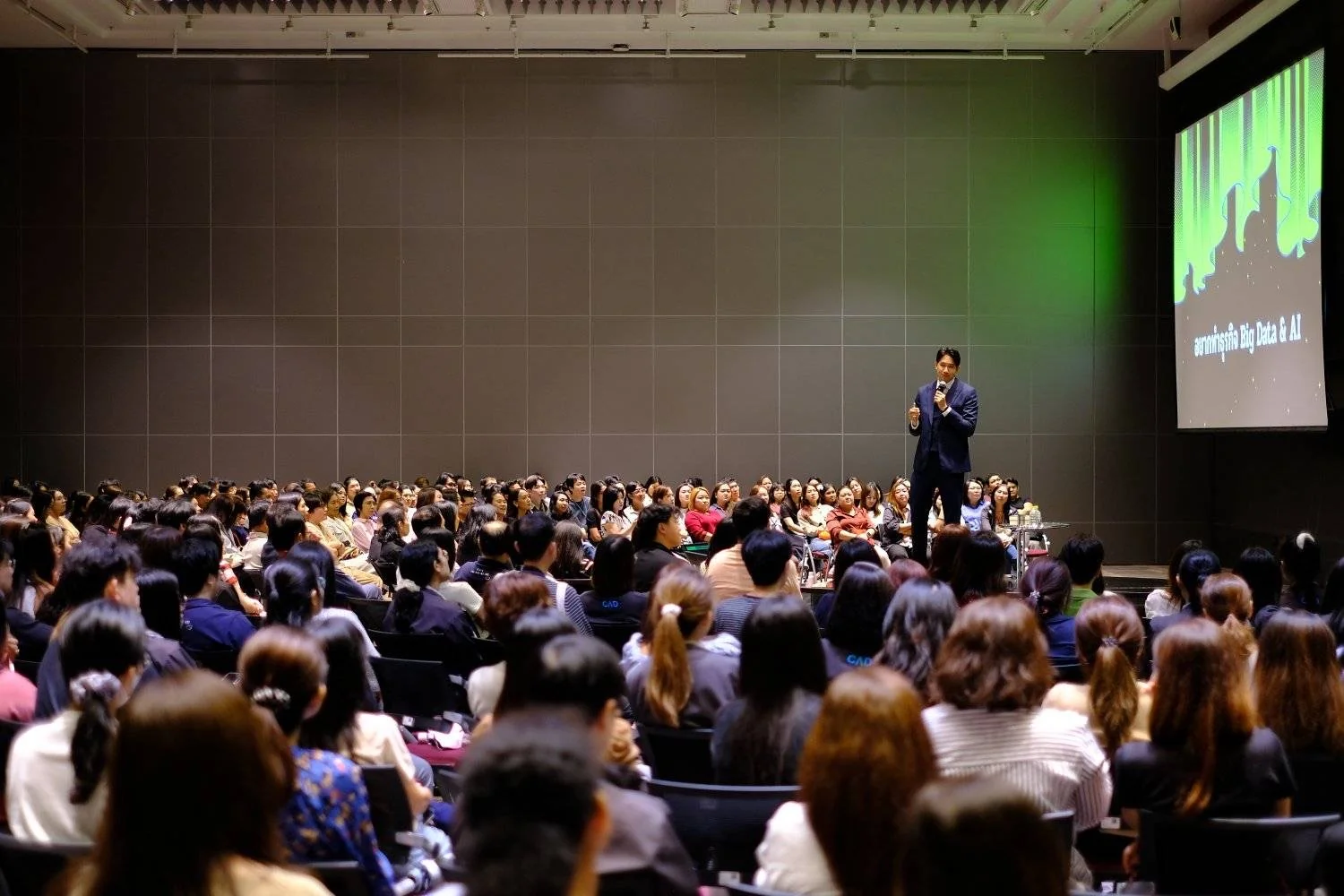 A speaker on stage before a large business audience.