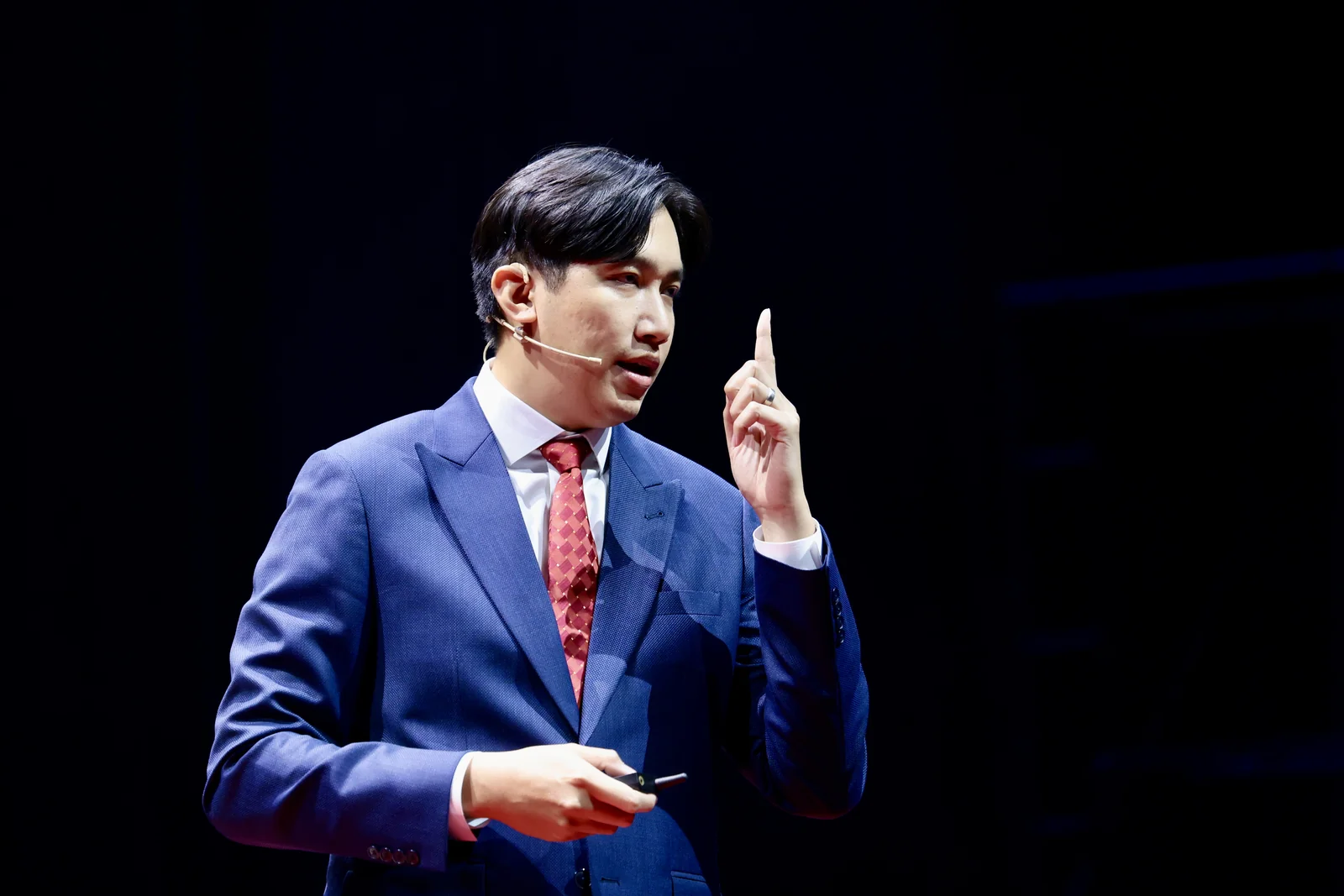 A speaker explaining a point on a dark stage.
