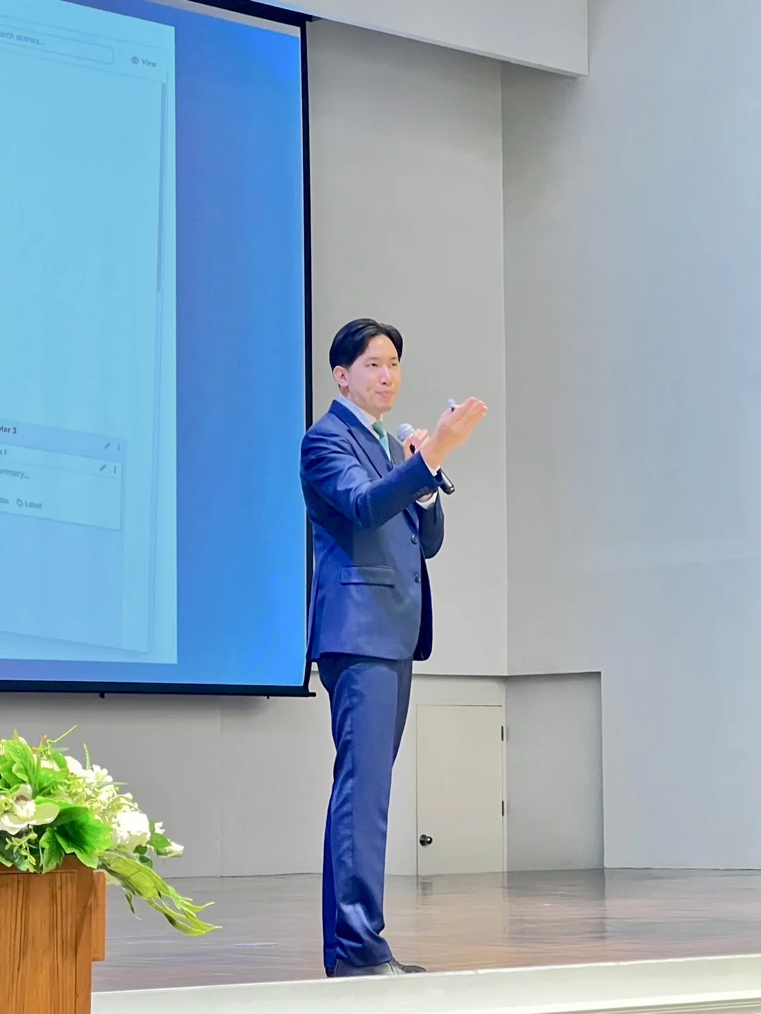 A speaker addressing a learning session beside a presentation screen.
